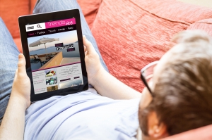 modern technology concept: young man reading a trends blog at tablet pc on the sofa