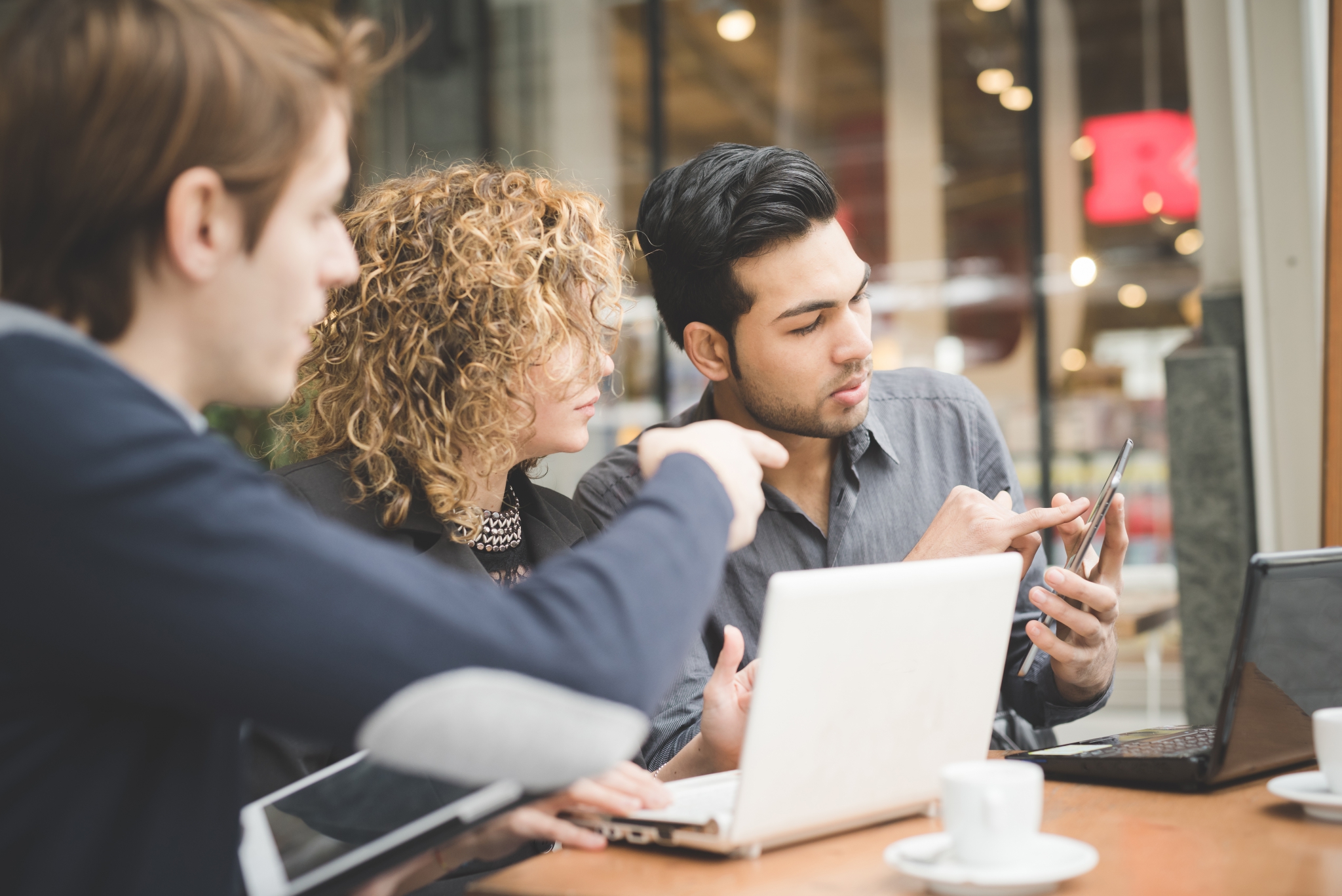 Multiracial business people working outdoor in town Multiracial business people working connected with technological devices at the bar