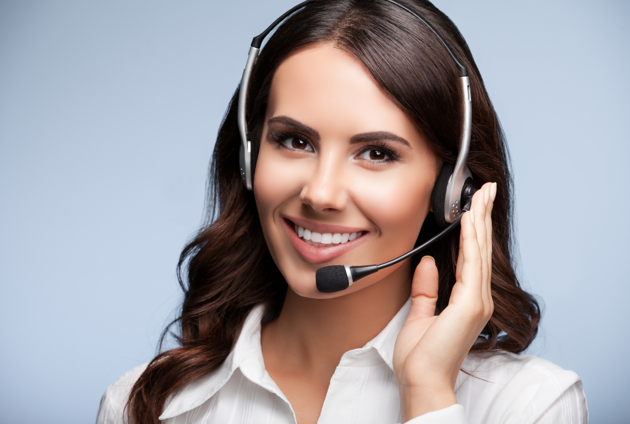 Portrait of happy smiling customer support female phone operator in headset, against grey background. Consulting and assistance service call center.