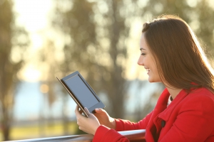 Woman reading an ebook in a balcony at sunset in winter